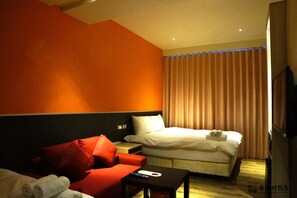 A hotel room with a bed, a red sofa, a small table, and a TV. - ColorMix Hotel & Hostel (Taipei)