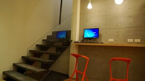 A modern interior with a staircase, two red bar stools, and a computer monitor on a wooden counter. - ColorMix Hotel & Hostel (Taipei)