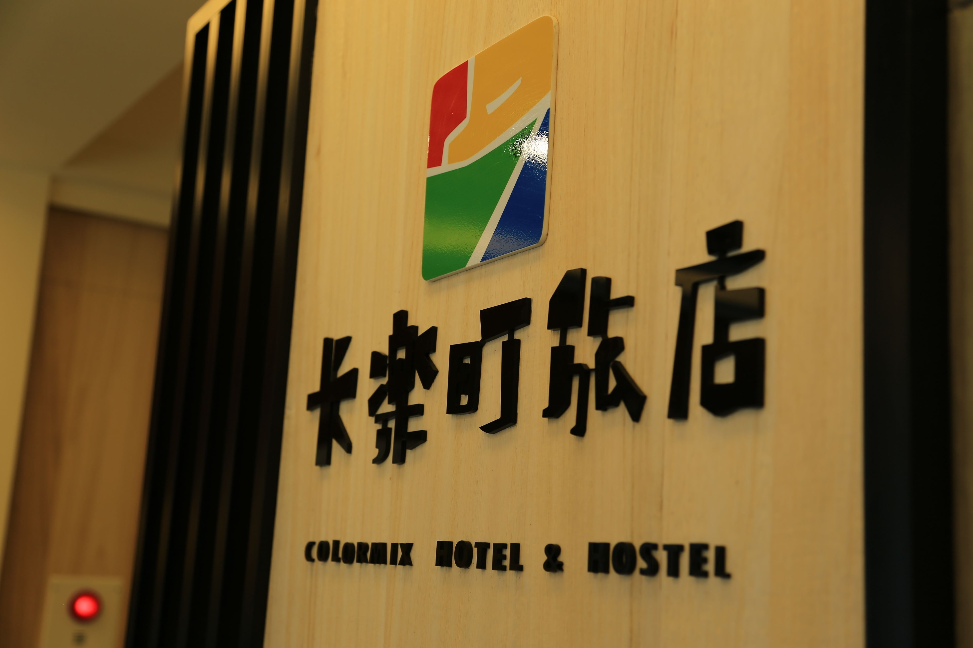 Placa do Colormix Hotel & Hostel com um logotipo colorido e caracteres chineses.