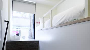 Una escalera con acabado de madera y una pared blanca con una franja gris.