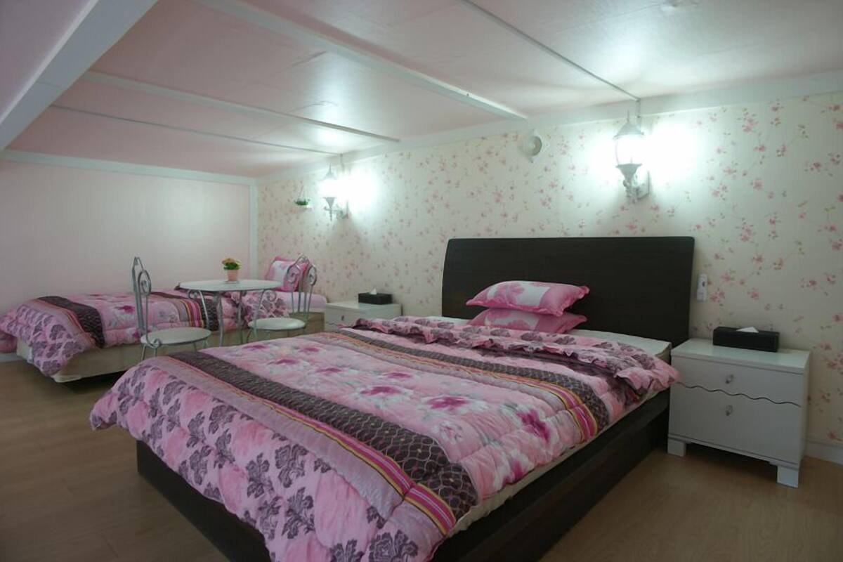 A bedroom with two beds, a desk, and a chair.