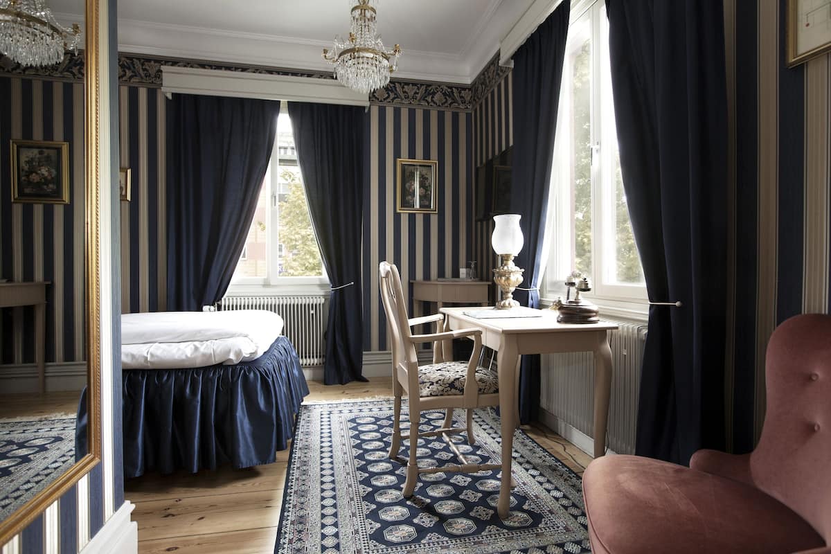 Una habitación con una cama, una silla, una mesa y una ventana.