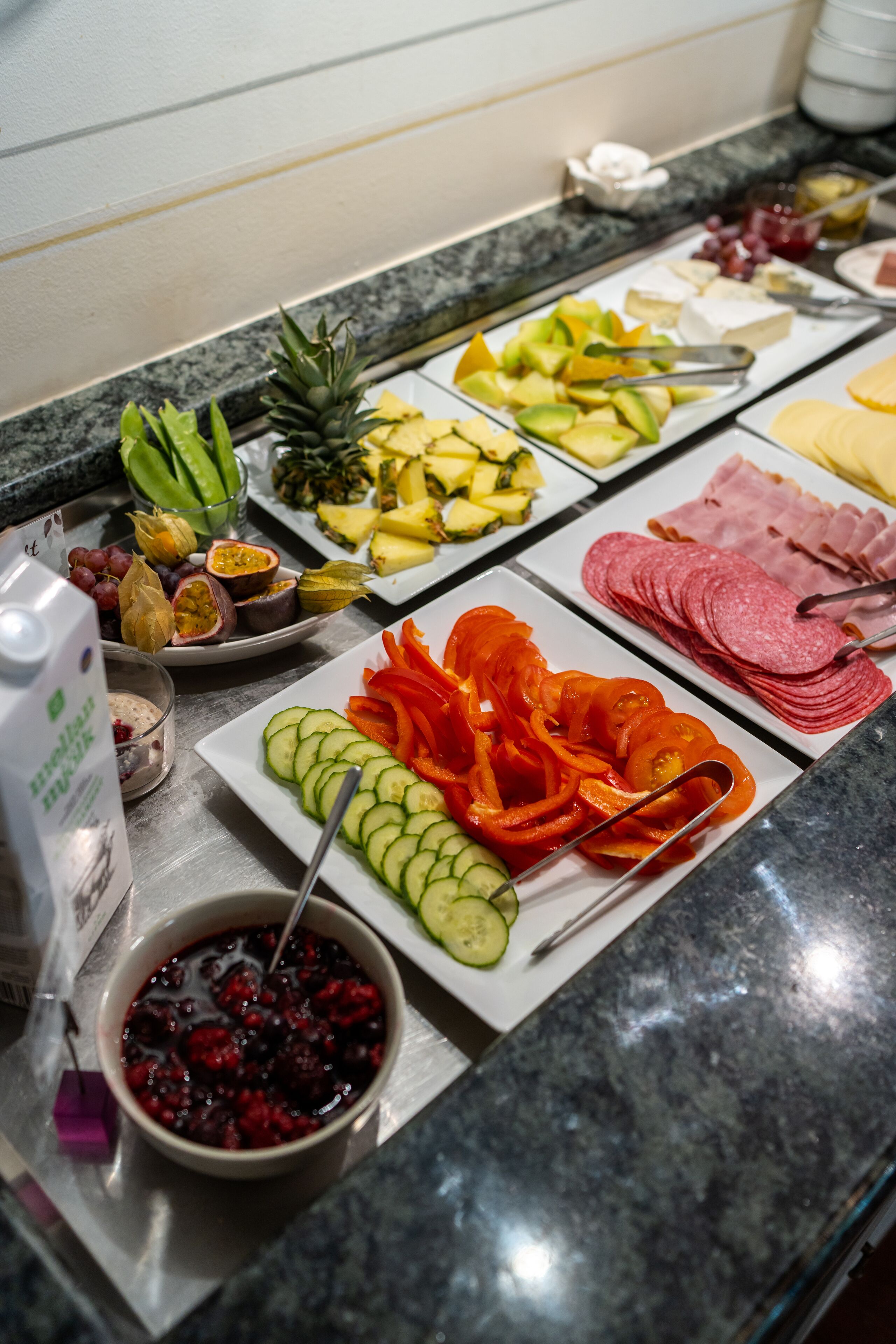 Un bufé con diversos alimentos, entre ellos frutas, verduras y embutidos.