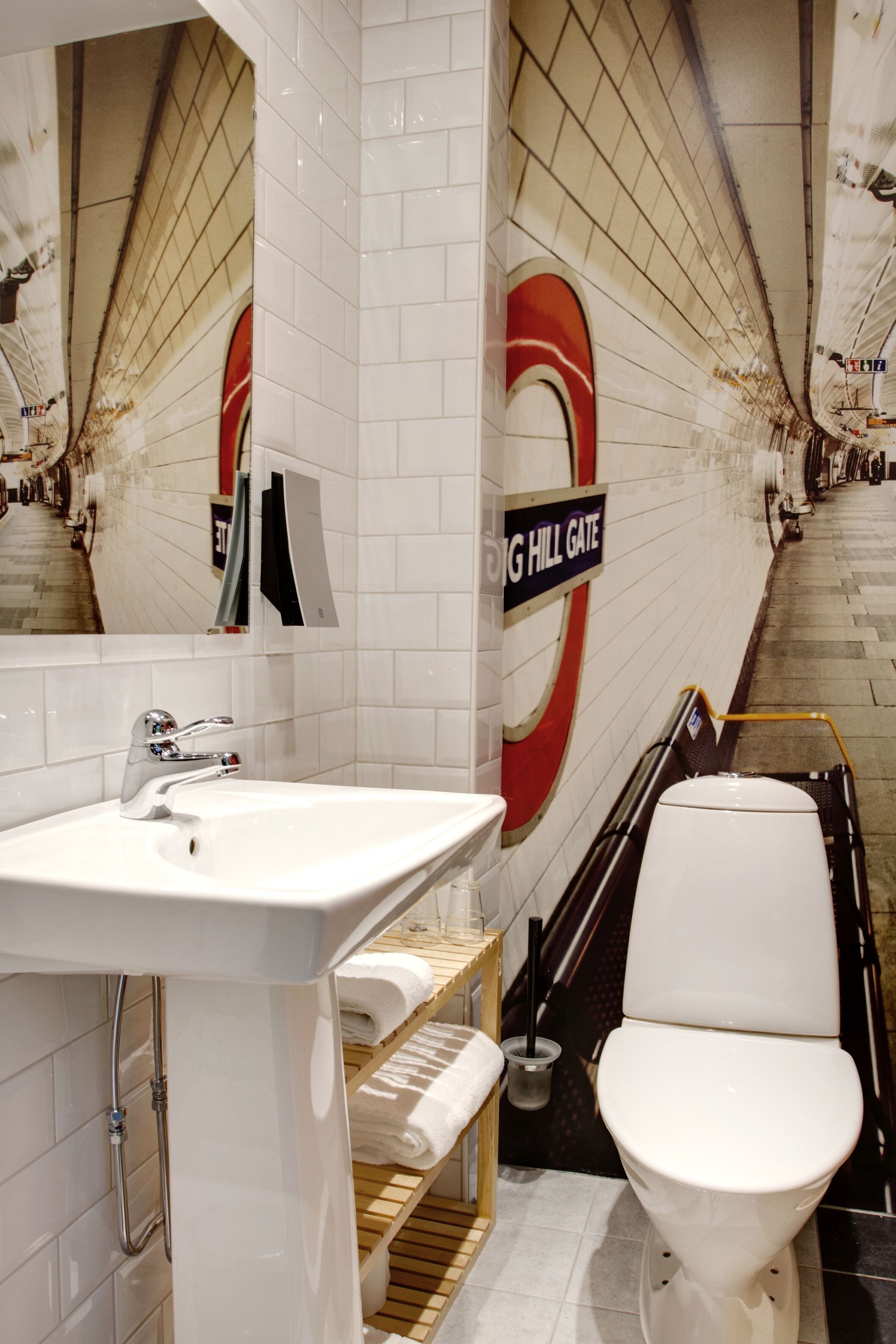 Ein modernes Badezimmer mit einem weißen Waschbecken, einer Toilette und einem Spiegel. An der Wand befindet sich ein Schild mit der Aufschrift "BIG HILL GATE".