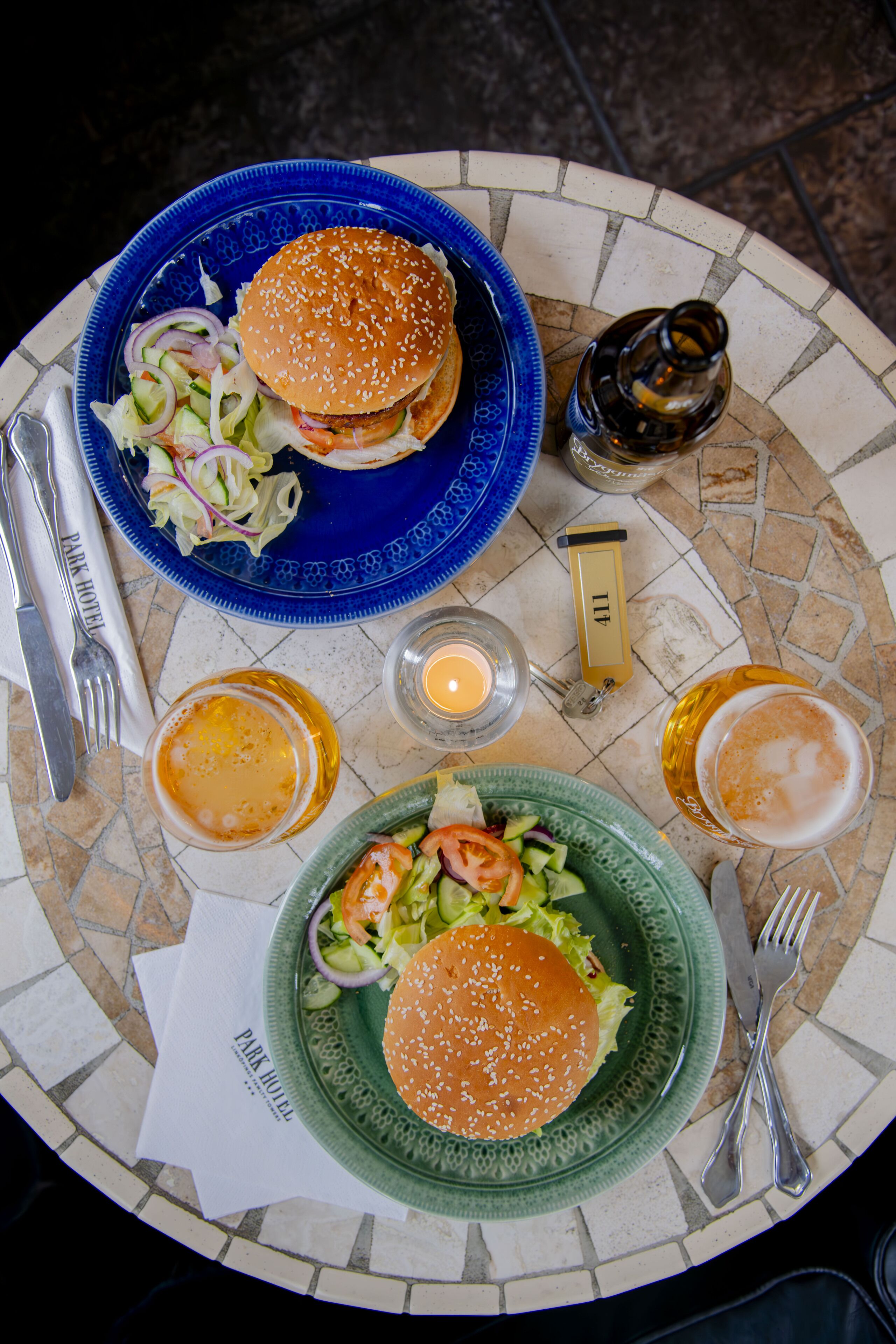 Una mesa con dos platos de comida, una botella y una vela.
