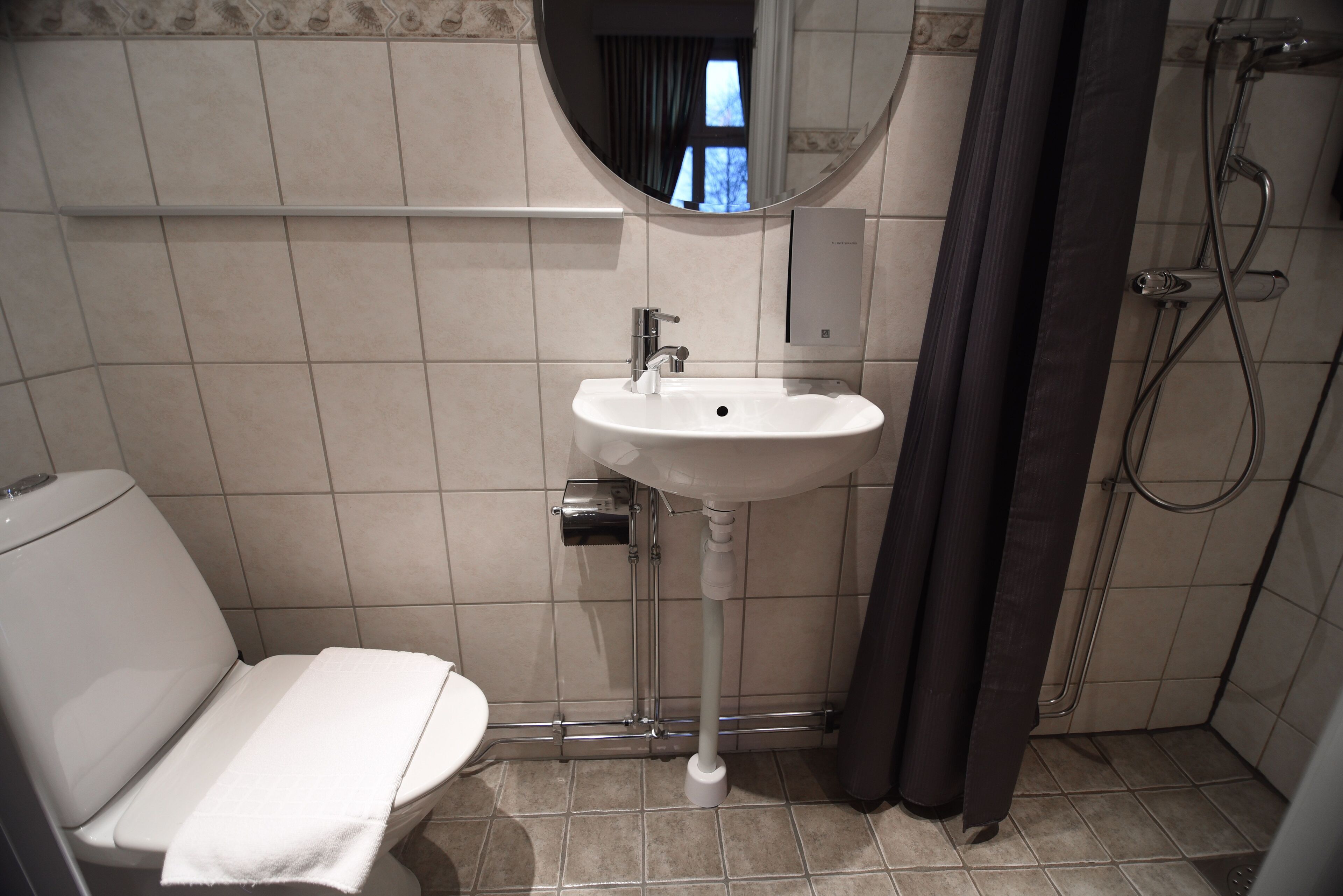 A bathroom with a toilet, sink, and shower.