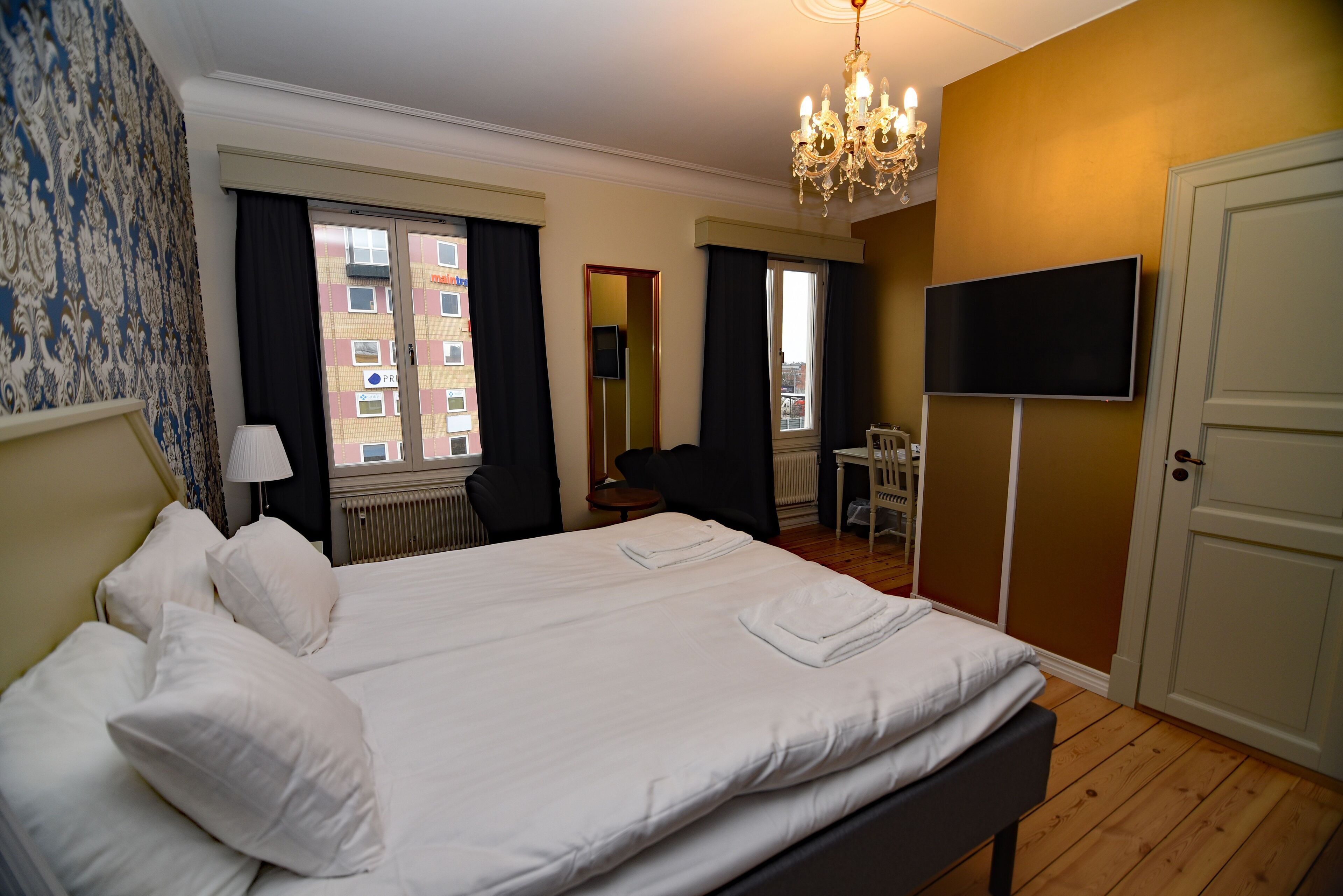A hotel room with a large bed, a television, a desk, and a chair.