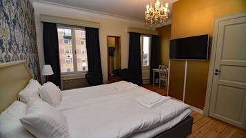A hotel room with a large bed, a television, a desk, and a chair.