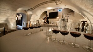 Une pièce dont l’intérieur est aménagé pour une dégustation de vin, avec une table dressée, plusieurs verres à vin et une bouteille.