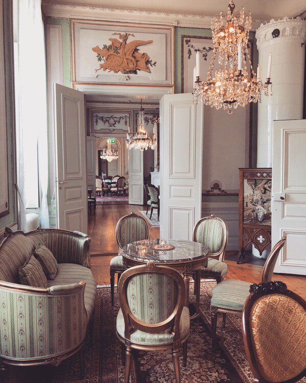 A formal dining room with a chandelier, ornate chairs, and a table set for four.