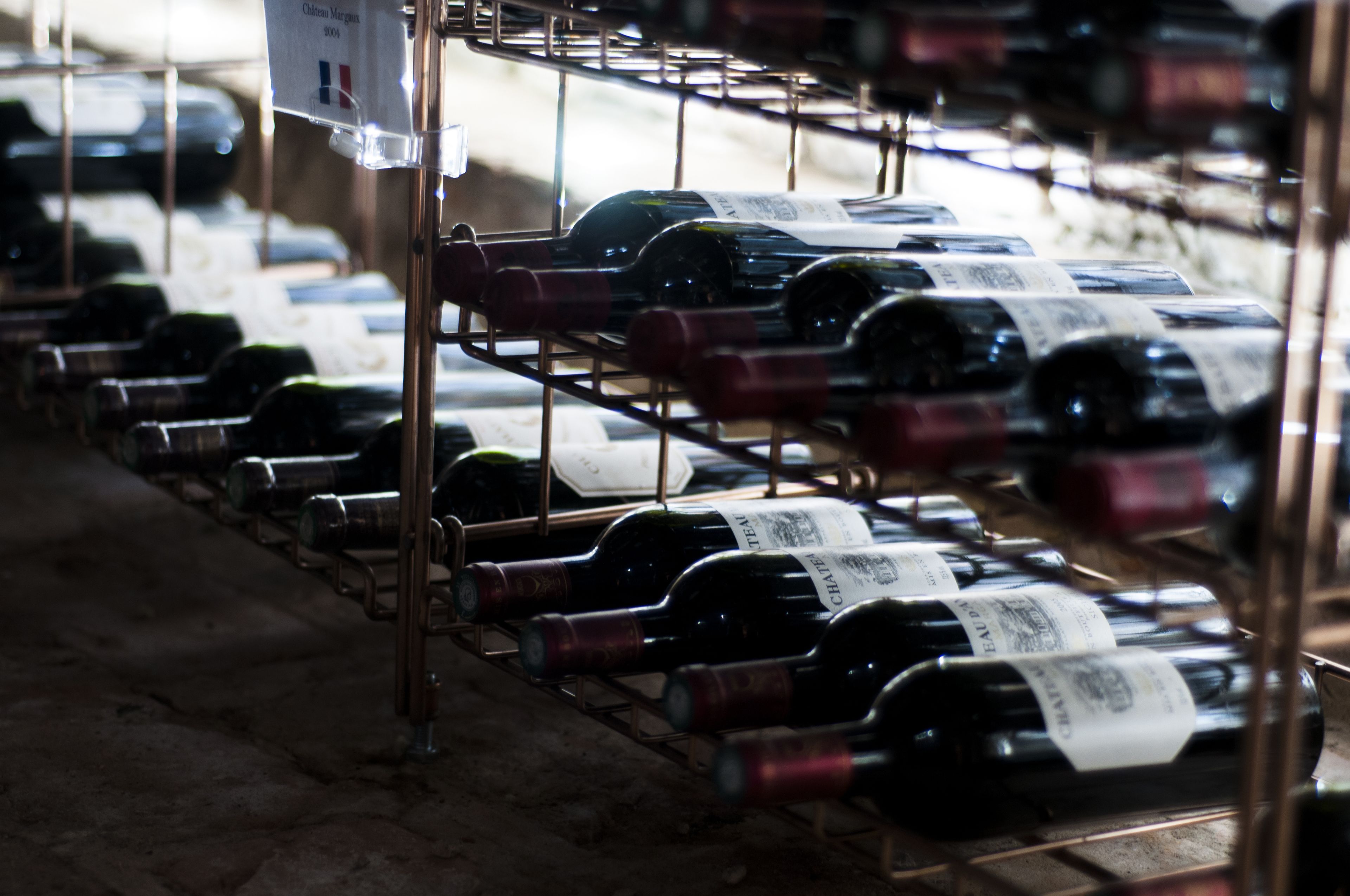 A storage area with rows of wine bottles on metal racks.