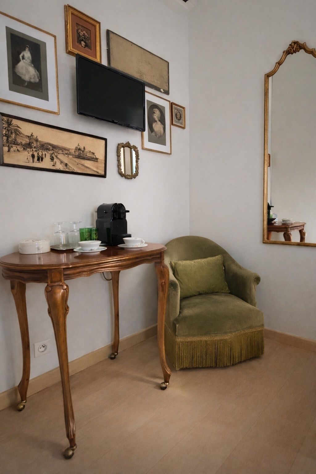 A room with a wooden table, a green armchair, and a large mirror.