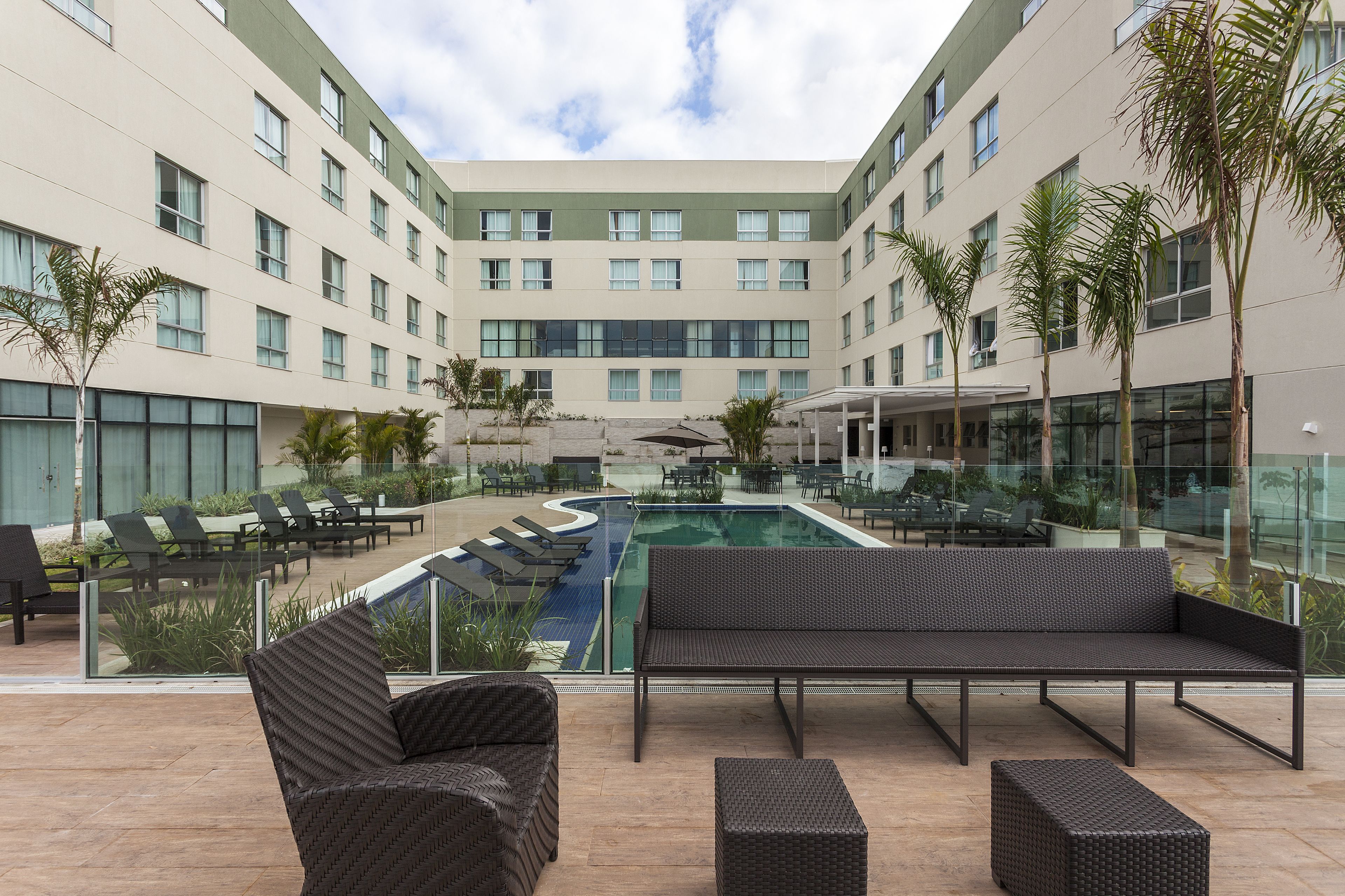 A modern hotel courtyard with a swimming pool, lounge chairs, and a seating area.
