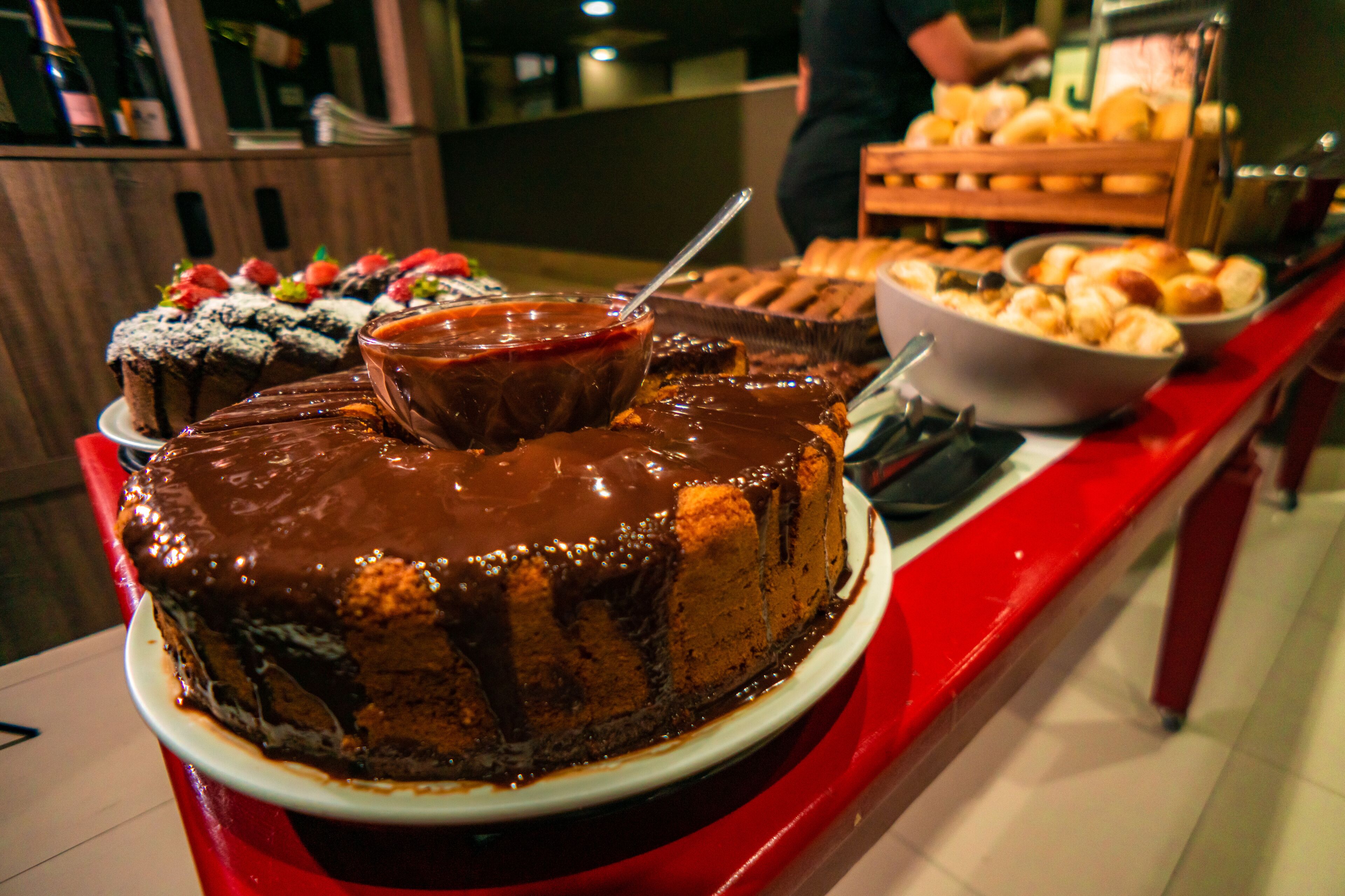 Una mesa de buffet con diversos postres, incluyendo un pastel de chocolate, frutas y repostería.
