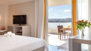 Habitación de hotel con cama, televisión, balcón con mesa y sillas, y vistas de la ciudad.
