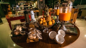 Un bufé de desayuno con una variedad de frutas, bebidas y acompañamientos sobre una mesa de madera.