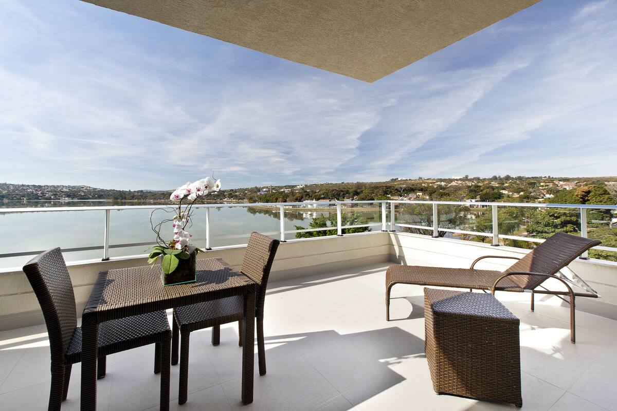 A balcony with wicker furniture, a table, and a potted plant.