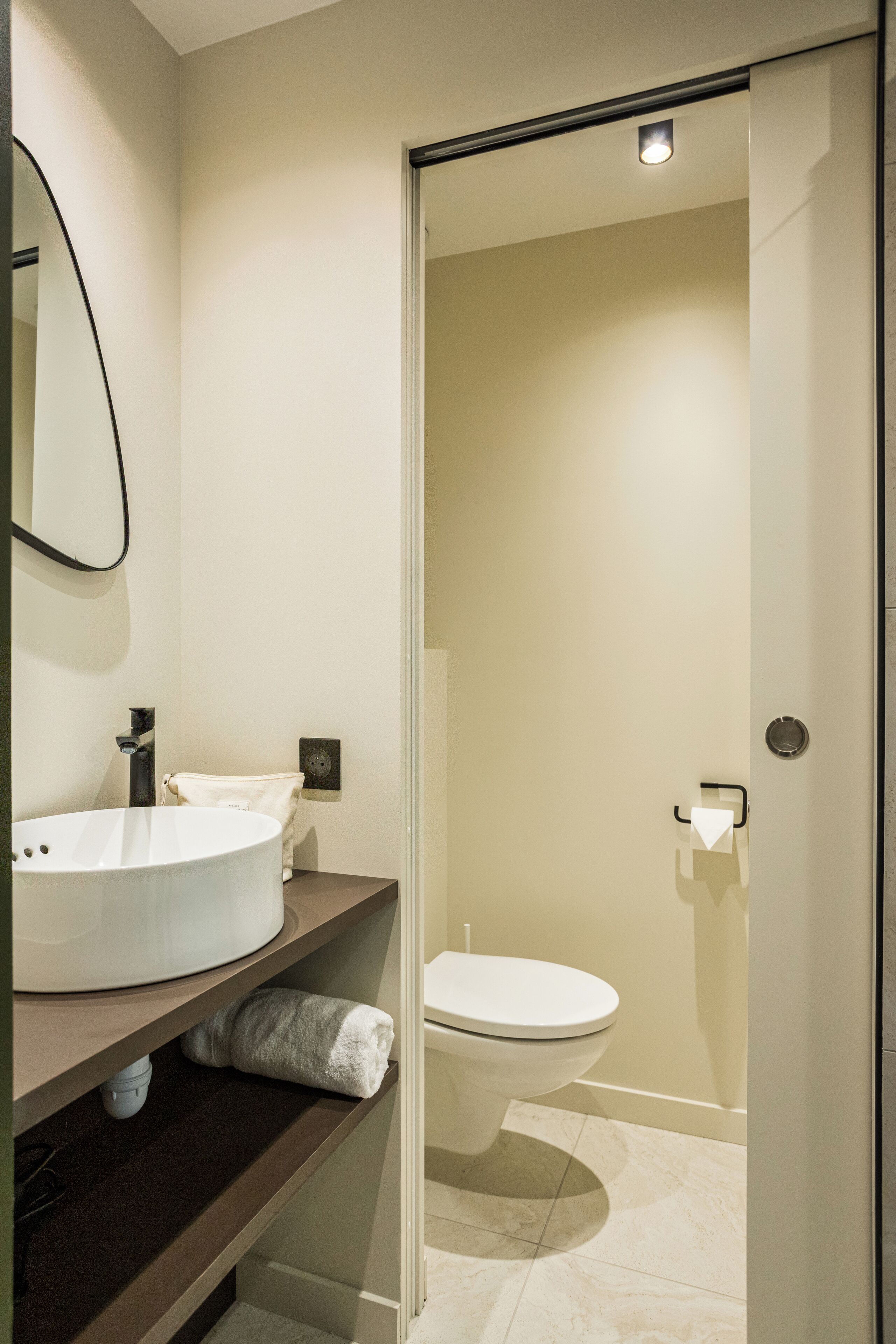 A modern bathroom with a large white sink, a mirror, and a toilet.