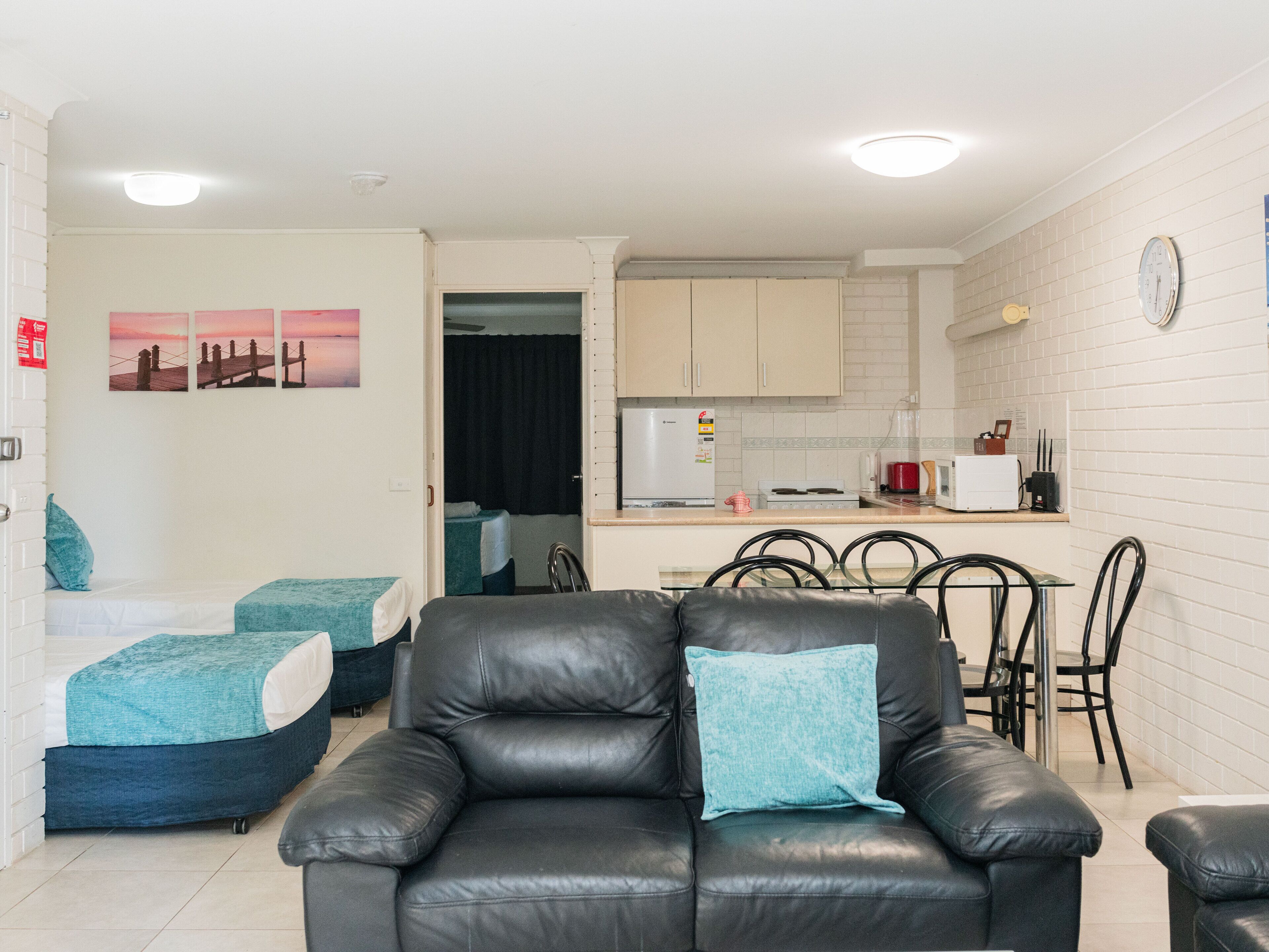 A compact living space with a kitchenette, a dining area, and a seating area with a sofa and chairs.