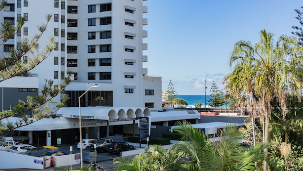 A high-rise hotel with multiple floors, a reception area, and a parking lot. - Trickett Gardens Holiday Inn (Surfers Paradise)