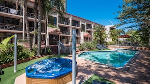 A hotel with a swimming pool, a hot tub, and a covered outdoor area with lounge chairs. - Trickett Gardens Holiday Inn (Surfers Paradise)