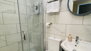 A bathroom with a glass-enclosed shower, a white toilet, a sink with a mirror, and a towel hanging on the wall. - Euro Bar and Hotel (Oxford)