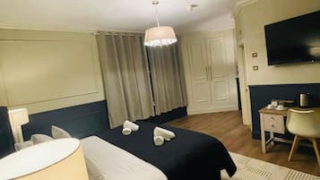 A hotel room with a bed, a desk, a TV, and a chandelier.