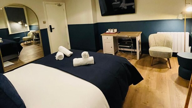 A hotel room with a large bed, a desk, a chair, a television, and a mirror. - Euro Bar and Hotel (Oxford)