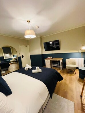 A hotel room with a large bed, a desk, a chair, a television, and a mirror. - Euro Bar and Hotel (Oxford)