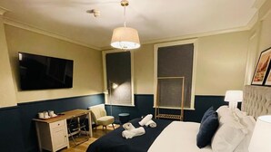A bedroom with a bed, bedside tables, a desk, a chair, a TV, and a ceiling fan. - Euro Bar and Hotel (Oxford)