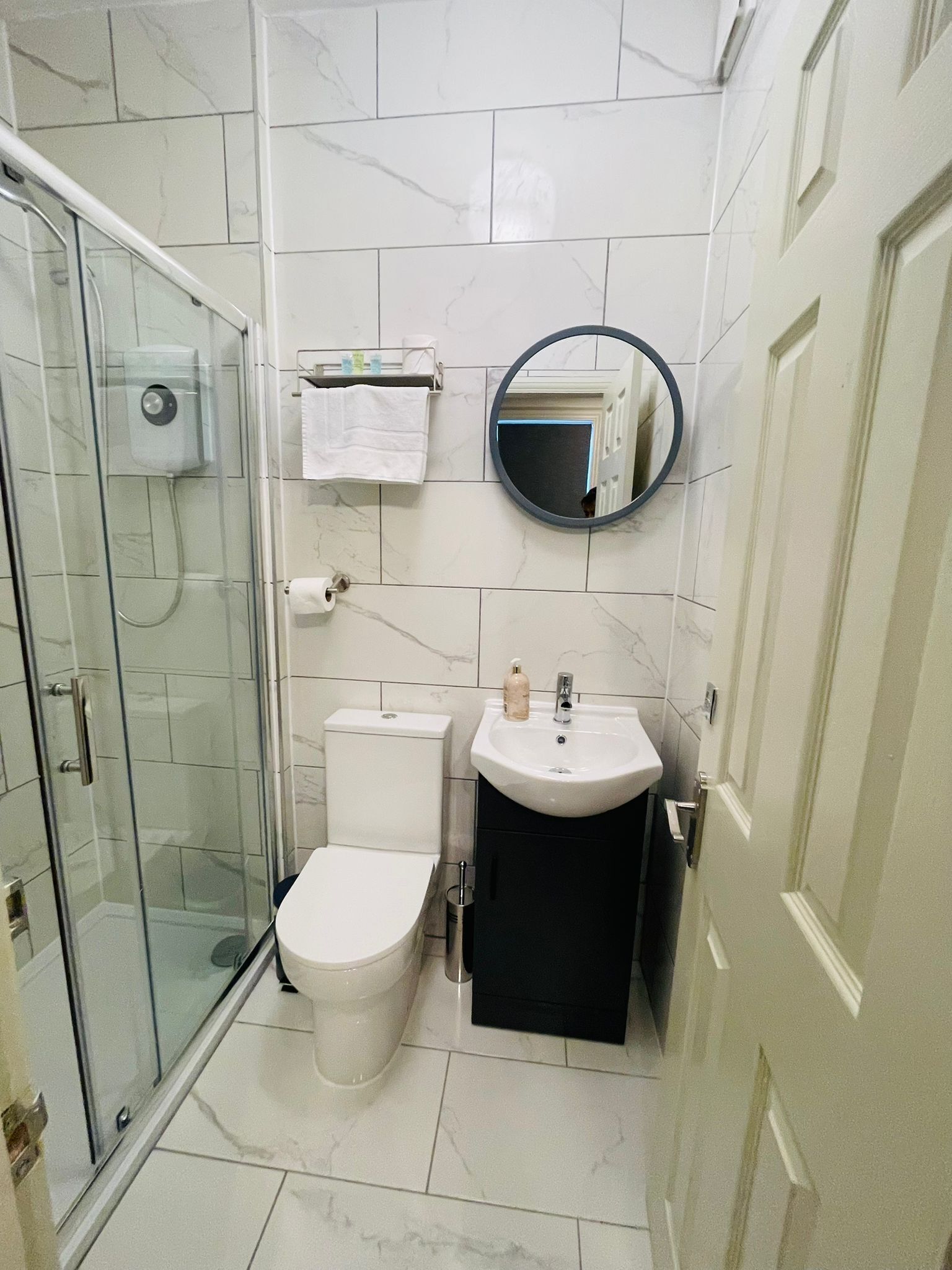 Une salle de bain avec une douche à parois de verre, des toilettes, un lavabo et un miroir.
