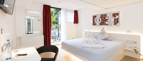 Une chambre d’hôtel moderne équipée d’un lit, d’un bureau, d’une chaise et d’un téléviseur.