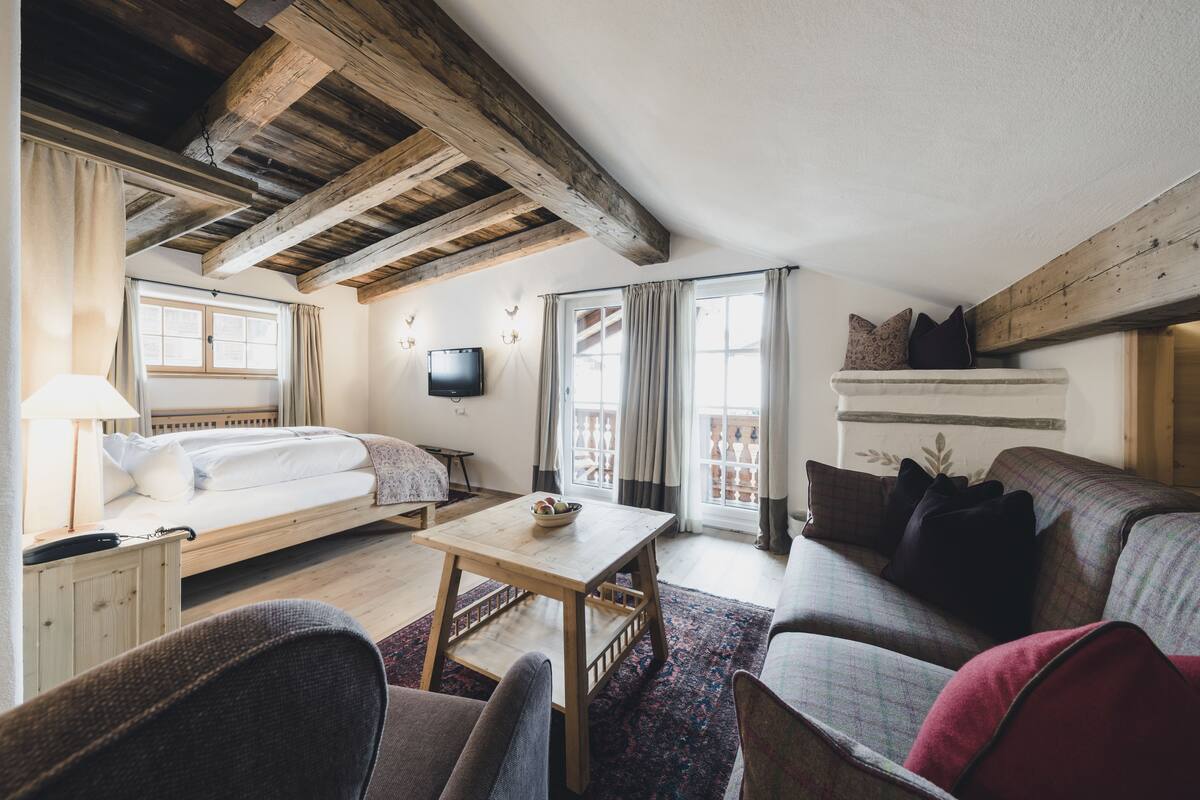 A cozy room with a bed, a sofa, a small table, and a TV.