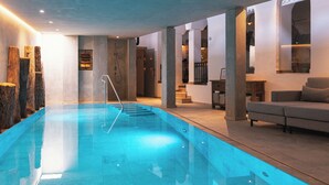 Una piscina interna moderna con elemento d'acqua cristallina, dettagli in pietra e un design d'interni contemporaneo.