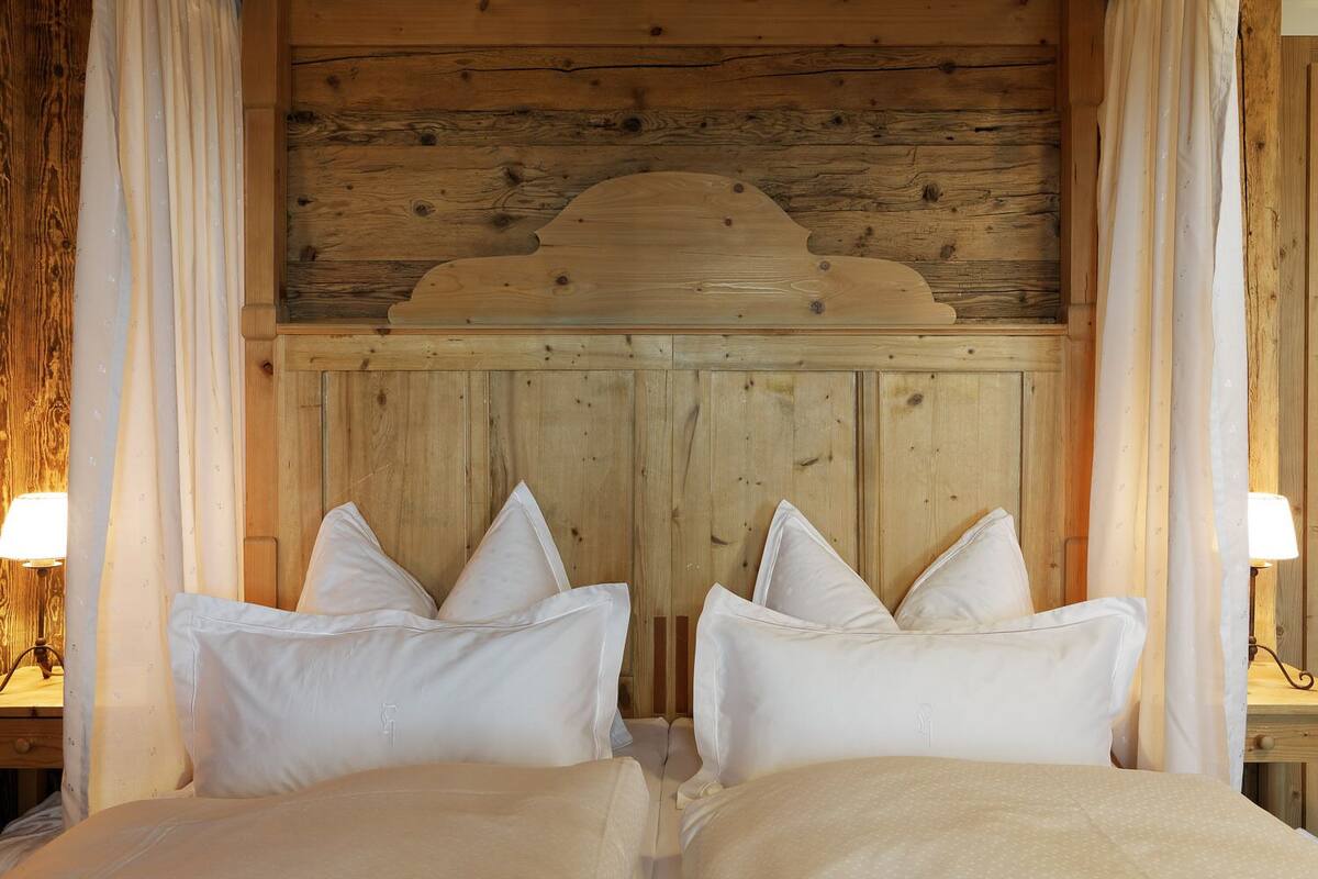 A double bed with white linens and pillows, set against a wooden headboard with a decorative arch.