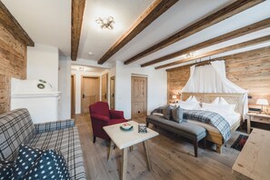 A cozy room with a bed, a red armchair, a sofa, and a small table. - Himmlhof (Sankt Anton am Arlberg)