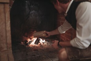 A person loading a log into a wood-fired oven. - Himmlhof (Sankt Anton am Arlberg)