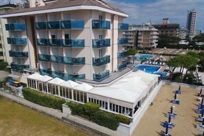 Un hotel de varios pisos con balcones, una zona de piscina y un área de estar al aire libre techada.