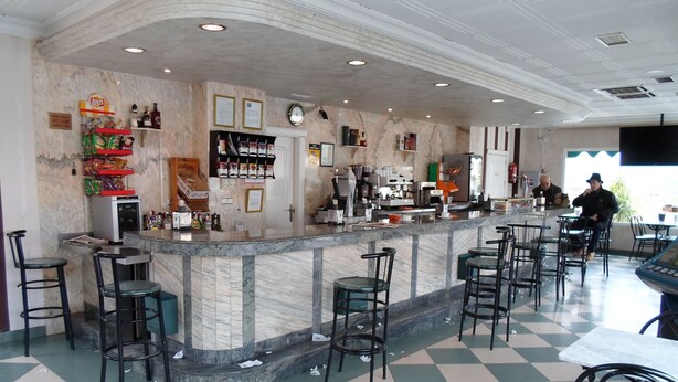 A bar area with a marble counter, multiple stools, and a checkered floor. - Hotel El Doncel (Atarfe)