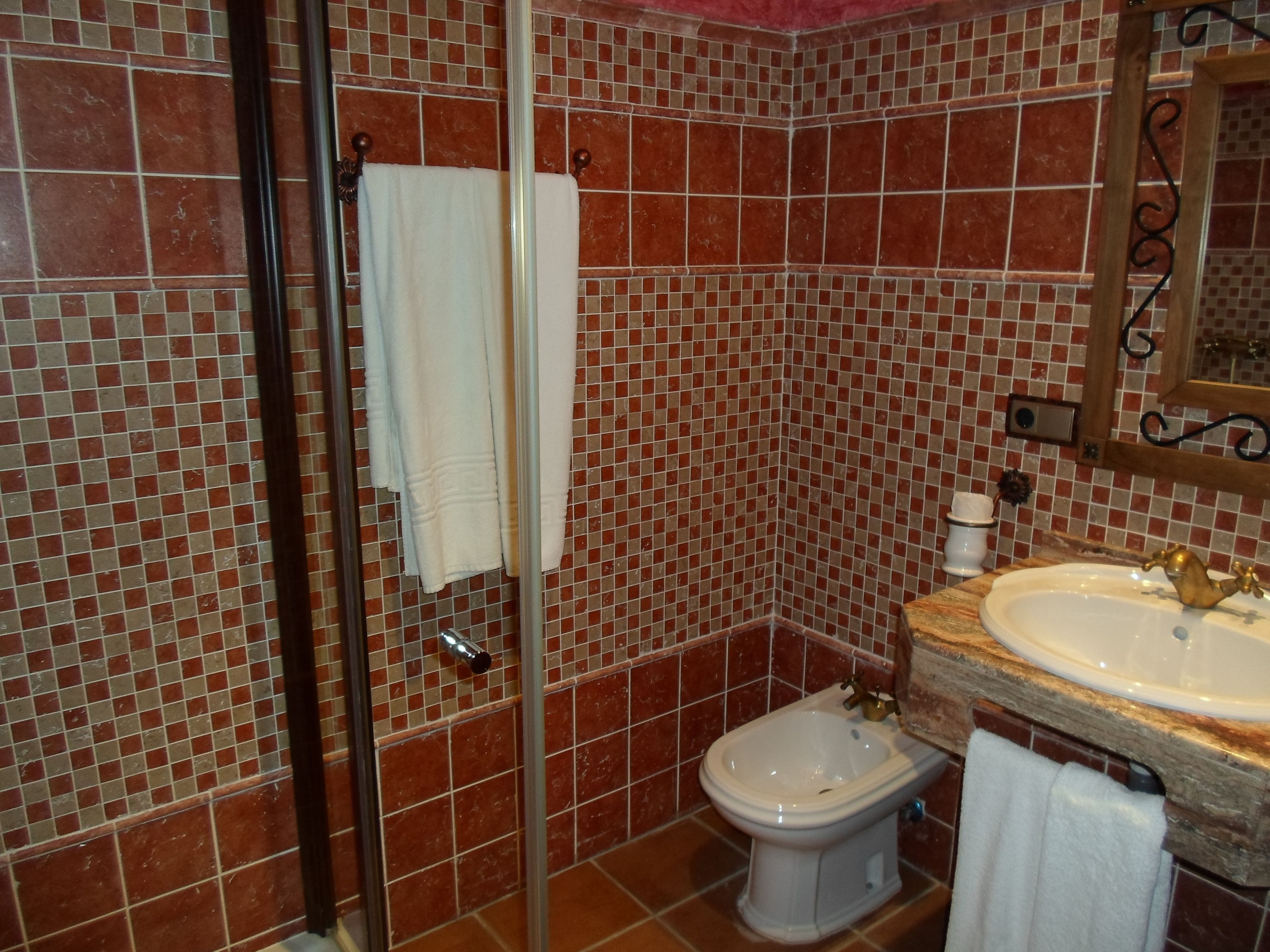 Un baño con cabina de ducha de vidrio, un bidé y un lavabo con espejo superior.