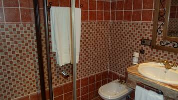 Un baño con cabina de ducha de vidrio, un bidé y un lavabo con espejo superior.