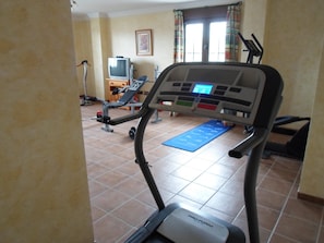 A home gym with a treadmill, exercise bike, and weights. - Hotel El Doncel (Atarfe)