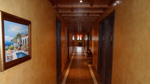 A long hallway with tiled flooring, wooden doors, and a framed painting on the left wall. - Hotel El Doncel (Atarfe)
