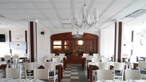A dining area with checkered flooring, white tables, and chairs. - Hotel El Doncel (Atarfe)