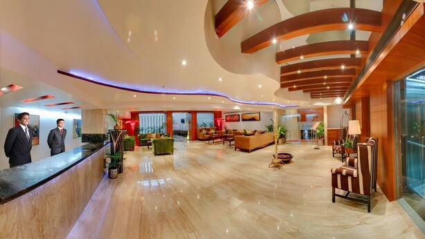 Un moderno vestíbulo de hotel con mostrador de recepción, zona de estar y una escalera.