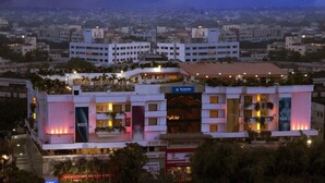 Un hotel con varios pisos, un jardín en la azotea y vistas panorámicas de la ciudad al fondo.