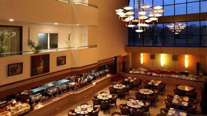 Un restaurante espacioso con varias zonas de comedor, un techo alto y grandes ventanales que dejan entrar luz natural.
