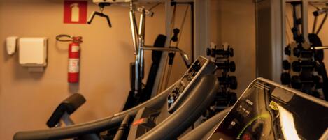 Une salle de sport équipée de tapis de course, de vélos d’appartement et d’appareils de musculation.