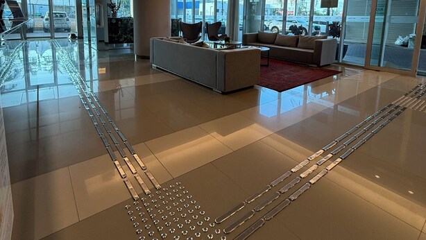 A spacious lobby with a modern design, featuring a large seating area, a glass partition, and a reflective floor. - San Diego Suítes Veredas Sete Lagoas (Sete Lagoas)