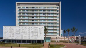A modern hotel with a flat facade, multiple balconies, and a large decorative panel with various patterns. - San Diego Suítes Veredas Sete Lagoas (Sete Lagoas)